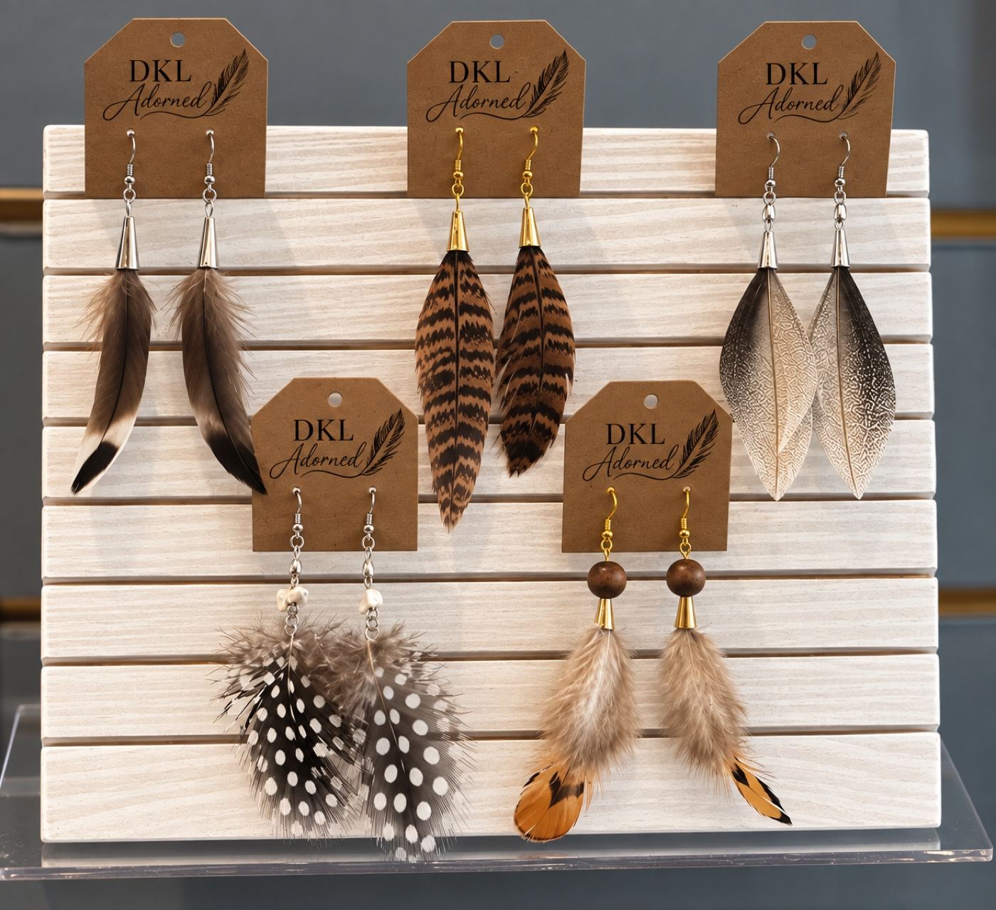 Feather earrings on a wood stand with DKL Adorned tags